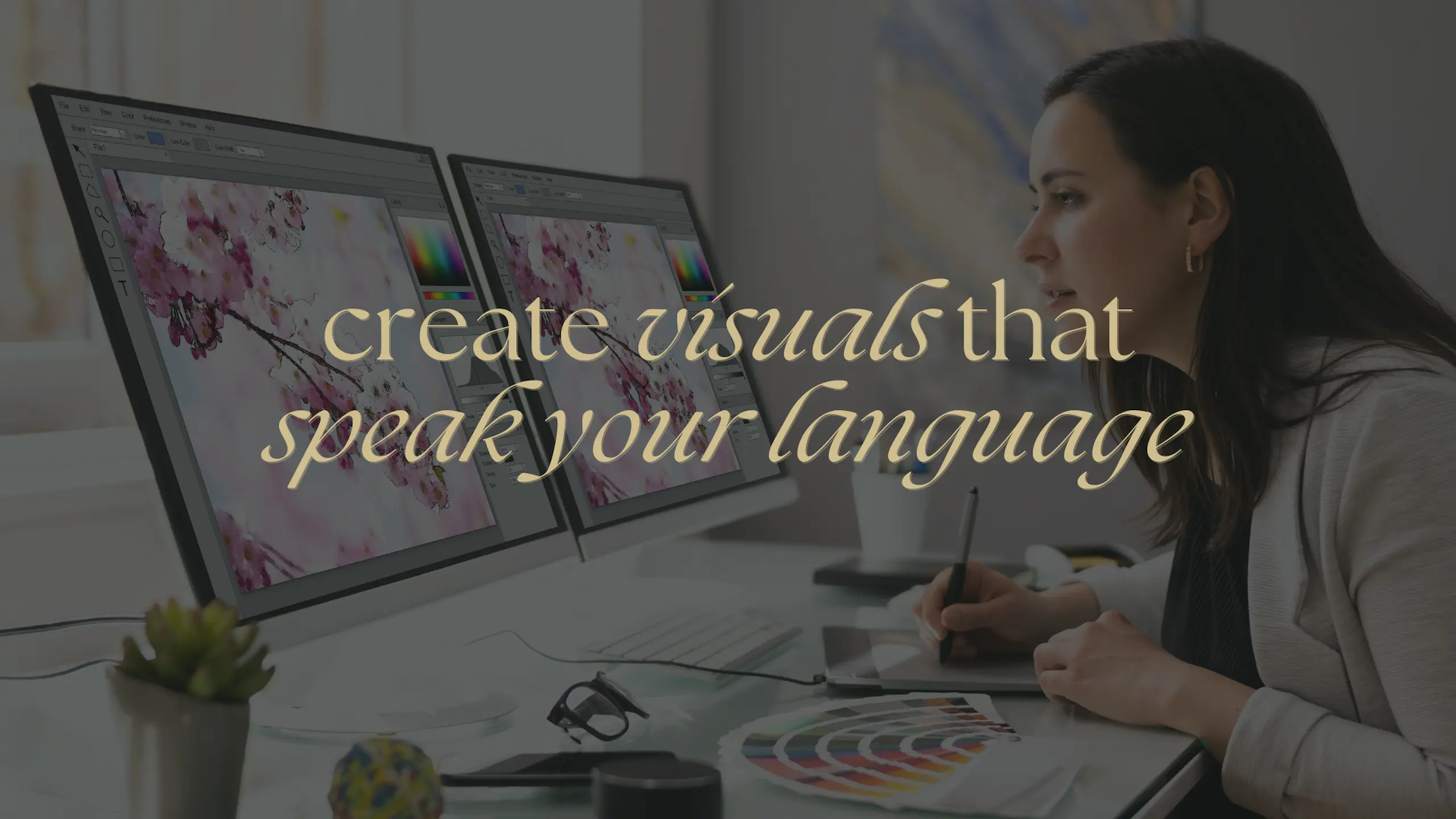 Frau gestaltet an zwei Monitoren ein visuelles Design mit Farben und Grafiken. Textaufschrift: create visuals that speak your language.